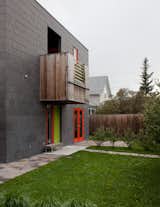A handful of boxy protrusions on the facade give the modernist residence an additional three-dimensionality. The colorful window frames and door also give variety and depth to the gray structure.