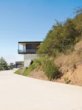 To deal with a Malibu site’s sharp incline, architect Bruce Bolander set the steel, concrete, and glass house on caissons. A deep wraparound porch nearly doubles the home’s living space and offers the ideal perch for outdoor dining and taking in spectacular views of the surrounding canyon. The garage serves as resident Dave Keffer’s home office. Photo by J Bennett Fitts.