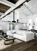 Living Room, Sofa, Coffee Tables, Medium Hardwood Floor, and Pendant Lighting A 200-year-old factory in Umbria is transformed into an inviting home by designer Paola Navone. In the seating area, a trolley found at a flea market functions as the coffee table alongside an expansive Navone-designed sofa for Linteloo. Custom pendants by photographer Mark Eden Schooley hang above the dining table. Photo by Wichmann + Bendtsen.  Search “juicy salif citrus squeezer white” from A Converted Factory Building in Italy