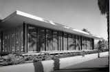 The restored exterior of the building is a virtual match to the one shown in this photograph shot by Julius Shulman in 1960. Anodized aluminum solar screens slide and keep out the bright desert sun while allowing visibility to the street.  Photo 1 of 5 in Iconic Midcentury Bank Repurposed in Palm Springs by Lawrence Karol