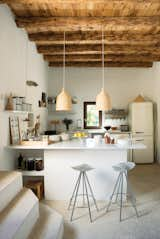 In Nani Marquina's serene home in Ibiza, Jamaica barstools by Pepe Cortès for Knoll and two Ikea pendants pair nicely with the plaster walls, restored wooden beam ceilings, and polished cement floors in the kitchen.