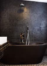 Black tiles and fittings lend the bathroom a dramatic look. The black bathtub is made of recycled plastic. Photo by Per Magnus Persson.