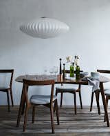 A Dwell table, featuring Juniper’s Edge Table and Cross Chairs, a Nelson Bubble Lamp, HAY glassware, and Applicata candle holders.