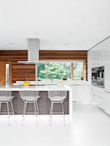 Kitchen, Wall Oven, Range Hood, White Cabinet, and Wood Cabinet Bertoia bar stools by Knoll are tucked under the island in the Scavolini Scenery kitchen. Jordan replaced the original wood flooring with white resin, a robust surface used in high-traffic environments.  Photo 5 of 12 in The Midcentury Spirit is Alive and Well in This Hudson Valley Escape