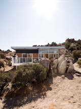 Outdoor, Boulders, Trees, Small Patio, Porch, Deck, Back Yard, Wood Patio, Porch, Deck, Metal Patio, Porch, Deck, and Desert The Blue Sky prototype house leads a second life as desert getaway for David McAdam and his partner Scott Smith.  Photo 1 of 10 in Small “Hybrid Prefab” Home in the Desert