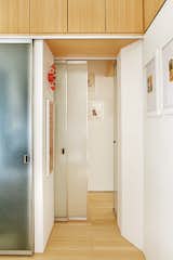 Hallway and Light Hardwood Floor The architects designed the bamboo-plywood storage compartments above the hallway, bathroom, and bedroom closet.  Photo 7 of 12 in Bright Renovation of a Tiny Manhattan Apartment