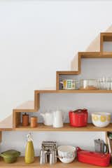 There's typically a lot of wasted space beneath stairs. With some proper forethought, the framing can be placed in such a way to allow installation of recessed shelves, which showcase the homeowner's colorful collection of midcentury kitchen items.&nbsp;