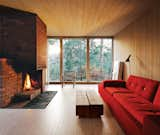 Living Room, Sofa, and Standard Layout Fireplace The interiors are clad in white-glazed pine, a contrast to the black-stained facade. The brick fireplace is original. Near a Polder sofa by Hella Jongerius for Vitra is a coffee table of Sævik’s design. The rocking chair is vintage and came with the house.  Photo 2 of 9 in Richly-Surfaced Wood Interiors by Zach Edelson from Cozy Scandinavian Abodes