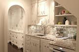 The kitchen is designed with white panel cabinetry, granite, and includes custom track lighting. Photo by Brittany L. Kimmel.