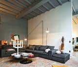 Living Room, Brick Floor, Sofa, Sectional, Floor Lighting, and Table Lighting The room also contains a sofa by Flexform, cushions from textile firm Chevalier Masson, a Jens Fager candelabra, and a painting by Roger Raveel.  Photo 1 of 1 in An Eclectic Living Room in Antwerp