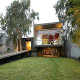 Outdoor, Grass, Decking Patio, Porch, Deck, Wood Patio, Porch, Deck, Walkways, Front Yard, and Trees The entrance is reached via a long ramp perforated by uplights.  Photos from A Modern Concrete Home in Peru