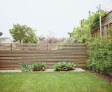 Outdoor, Horizontal Fences, Wall, and Grass The once-sloping space now has climbing vines, a slatted fence, and foxtail agaves.  Search “one bedroom became three space efficient san francisco renovation” from A Two-Part Landscaping Renovation in San Francisco