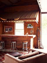 Dining Room, Bar, Chair, Stools, Rug Floor, and Ceiling Lighting Inside, Paul often dispenses whiskey to friends from behind the rustic bar.  Search “Bar-Method.html” from A Modern Farmhouse Recalls Old-Time Americana