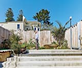 Outdoor, Vertical Fences, Wall, Small Patio, Porch, Deck, Concrete Patio, Porch, Deck, and Grass Russell-Clarke tends a small garden.  Search “San Franciscos Forgotten Modernism” from Striking Slatted Wood and Glass Home in San Francisco