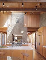 The house has the feel of a refined barn: The kitchen flows into the dining area, then into a den. The two PISE “chimneys” serve to demarcate the transitions and visually unite the space.