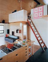The kitchen cabinets with cutouts for handles were designed by a local woodworker. The stairs lead to a loft office where Joanna works, perched beside a quilt made by her great-grandmother.