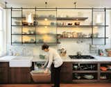 The homeowners' new kitchen is clean, modern, and laced with industrial touches (laboratory faucets, lab glass pendant lamps designed by Sand, stainless steel appliances), while animated by materials and crafted with elements that radiate warmth.