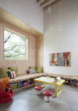In the playroom, built-in casework offers storage for toys. The yellow table was custom-built by the Kristin's father. The clear pendant lights are by Muuto. The "toy zone" is adjacent to the kitchen so that Lowell and Kristin can prepare meals and keep an eye on their yound children, aged three and five. "The residents wanted as little freestanding furniture as possible," Guess says. 'We did a lot of benches, which are made out of plywood so they're fairly inexpensive."