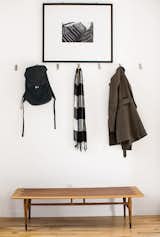 Inside the front door, coats hang from aluminum Bjärnum hooks by Ikea above a vintage Lane coffee table, which Magill bought from a coworker, and beneath a photograph by Beth Mercer.