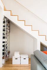 The staircase features a minimalist design with maple treads and edges. The alcove beneath the stairs allows Magill to stash things where they can still be easily accessed. The metal shelving system is another coworker castoff.