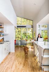 Sarah Magill and Copa, her golden retriever, relax in the kitchen of her home in Kansas City, where an eco-quartz-topped island can be used as a dining table—one of the home’s many adaptable features. The Akurum cabinets and handles are from Ikea, as are the Franklin folding bar stools, and the appliances are compact models from Summit.