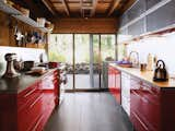 Kitchen, Colorful Cabinet, Metal Counter, and Stone Slab Backsplashe This sleek kitchen in the renovated Dolce and Burnham Residence hits warm notes with red lacquered cabinetry, cypress woodwork, and a leafy backyard vista.  Photo 6 of 6 in Ways to Use Gold Accents in the Kitchen by Erika Heet from Long Island Summer Home Gets a Modern Addition