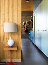 Working with a limited footprint, a daunting slope, and killer views, architect Bruce Bolander went vertical with a secluded canyon house in Malibu. A colorful, laminate-clad wall of storage stretches seamlessly from the kitchen to the bedroom, where a repurposed speaker stand serves as the bedside table. Photo by J Bennett Fitts.