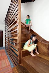 The walnut staircase and slide in a Chicago town house leads from the main level to the basement. To protect people on the ride down, a “crash pad” fashioned from a standard gymnastic mat covers the wall at the slide’s base.
