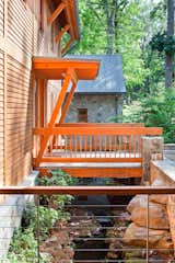 A stream runs under the orange entry bridge of the custom home built by Potomac Valley Builders.