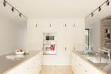 The twin kitchen islands are oriented parallel to the living room. The cabinet fronts are finished in white lacquer, with stainless-steel counters atop ash veneer.  Photo 6 of 15 in A Transformative Duplex Renovation in Montreal