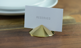 The Spot place card holders ($190 per see of four) are made from solid brass or crystal.