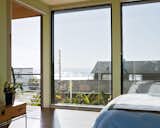 Floor-to-ceiling windows in the bedroom create the sensation of being outside, as if the entire house is one platform deck strategically shielded from the elements.  Photo 2 of 22 in Bedroom by Yu Wang from A Modern Coastal Home in Stinson Beach