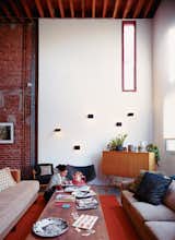 Living Room, Rug Floor, Sofa, Coffee Tables, Wall Lighting, Chair, and Storage Darcy Miro and her son, Lucien, enjoy a moment in their new double-height living room. The Charlotte Perriand wall sconces are vintage finds.  Photo 1 of 5 in A House Grows in Brooklyn from Lighting the Way: 5 Spaces that Sport Sculptural Illumination