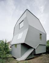 A playful twist on the concept of a pitched roof, the Just K house designed by AMUNT in Tubingen, Germany, features a monochromatic, blue-gray facade with strikingly skewed geometric forms. An exterior staircase leads to a separate entrance at the rear of the building, allowing the structure to be used as two separate units.