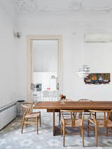 In the dining room, a Poul Henningsen lamp hovers over a table by Philipp Mainzer for E15, surrounded by Hans Wegner Wishbone chairs. The artwork is by Maria Sanchez. The designer added a Banco kitchen by Dada with Jasper Morrison stools.
