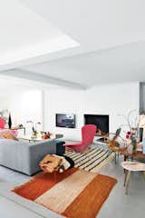 A pair of interior architects with a years-in-the-making furniture collection recast an old Belgian factory—in Bellem, a 25-minute drive out of Ghent and halfway to Bruges—as a playful family home. The stars of the living room are a pair of pink Bird chairs by Harry Bertoia for Knoll, accented by a brass-and-steel coffee table designed by homeowners as well as vintage marble-topped and wood occasional tables and antique rugs are from Morocco. Photo by Frederik Vercruysse.