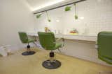 Lime-green retro barbershop chairs and Jielde's Loft Adjustable Arm Wall Sconces outfit the treatment area. Daltile's Rittenhouse subway tiles line the walls and Marmoleum from Forbo covers the floors.