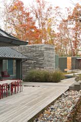 Outdoor, Walkways, Wood Patio, Porch, Deck, and Large Patio, Porch, Deck The dining table, a custom design by Formwork, and red Non chairs by Komplot complement the addition’s cypress cladding.  Search “divis-dining-table.html” from How This Landscape Design Made a Home as Fun as a Playground