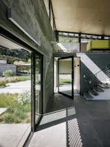 Doors, Metal, Sliding Door Type, Exterior, and Swing Door Type The entrance to the main pavilion is defined by a pivoting glass door from Fleetwood (above left). The stairs lead to the media loft, where Inga Sempé’s Ruché sofa for Ligne Roset breaks up the gray. Among the couple’s few directives were tall ceilings, which Feldman covered in low-cost plywood sheets.  Photo 7 of 9 in Entry walkway by Adam Brodsley from Sustainable Retirement Home in Tune with California Landscape