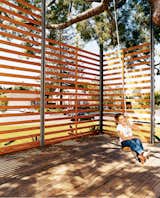 Gabriella swings on the rope swing hung from the podocarpus tree. The twenty-foot-tall, steel-framed, custom-built wood screen provides enough privacy to give the outdoor space the feeling of a room, with the 50-year-old polocarpus tree acting as a roof.