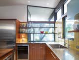 Opening the kitchen to outdoor spaces, a new window with floating shelves for storage looks out into the front yard.  New appliances, stainless steel countertops and an integral sink add utility. Photo by Whit Preston.  Photo 8 of 13 in Midcentury Renovation in Austin