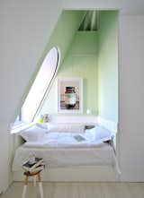 This four-level penthouse apartment in New York has some quieter moments (to contrast with the multistory reflective slide snaking throughout). Designed by architect David Hotson_Architect with interiors by Ghislaine Viñas, this top-floor bedroom is a minty moment of repose. Set into the dormer at the opposite side of the bedroom, the alcove bed occupies a wedge of space extending up to the attic-level oculus window. Photo: David Hotson.  Photo 5 of 7 in Brilliant, Light-Filled Attic Renovations by Aileen Kwun from Airy Attic Renovations