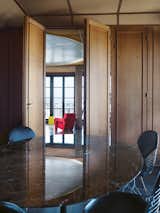 In 2006, Claus—director of Claus en Kaan Architecten, one of the Netherlands’ top architectural practices—finally got inside Perret’s apartment. He was duly impressed. “It’s the sheer abundance with which limited materials are used here that first struck me,” he says. “The wall-to-wall French oak paneling, combined with materials that were ahead of their time—columns made not from marble but from stone-blasted concrete, the extraordinary round plaster ceiling inset, and the fiber-wood paneling—and his attention to the tiniest of details.”

He tracked down the organization that owns the apartment, the Association Auguste Perret, to see if he and his wife could rent the unit as a pied-à-terre. To his surprise, they said yes. 

In the dining room, a marble-topped table by Eero Saarinen is ringed with Eames wire chairs. Through oak accordion doors, the atrium beckons with red Utrecht armchairs by Gerrit Rietveld and a yellow Diana table by Konstantin Grcic.