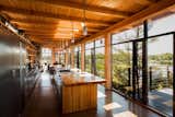 The home maintains remarkable material consistency, with Douglas fir cladding the beams, kitchen countertop, and interior walls. The open-plan kitchen absorbs views of the lake through an expansive glass wall.