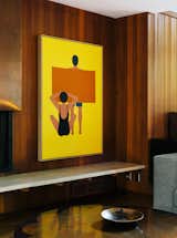In the living room, the painting is by Geoff McFetridge and the wood paneling is original to the house. “Jewel-y color and simple shapes—they feel right in this house,” says interior designer Jessica Helgerson.