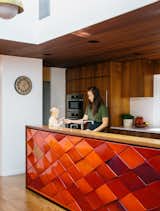 Aaron and Yuka Ruell transformed a 1950s Portland ranch house into a retro-inspired family home with plenty of spaces for their four children to roam. In the kitchen, interior designer Emily Knudsen Leland replaced purple laminate cabinets with flat-sawn eastern walnut, and added PentalQuartz countertops in polished Super White for contrast. The kitchen island is clad with original red tiles, and hanging cabinets above it were removed to maximize light and family-room views.
