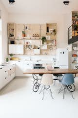 The kitchen is completely open to the main living area and features a custom birch pegboard wall. Eames dining chairs accent the space.
