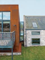Cor-Ten steel from a ship building yard clads the new structure, which connects via a glass "bridge" to a rebuilt stone farmhouse containing the bedrooms.