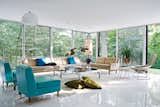 The living room, with vintage furnishings by Harry Bertoia, Paul McCobb, and others, overlooks the heavily wooded site, which adjoins a protected watershed. Goddard and Mandolene replaced the original tile floor with a glossy coat of resin and restored the original ceiling.