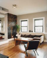 Peeling back plaster and drywall they unearthed beautiful brick walls. They opted to leave them exposed, letting light from the street and a wall of rough-hewn red brick warm up the large living rooms and kitchens. Mazza's living room sofa is from Crate and Barrel.